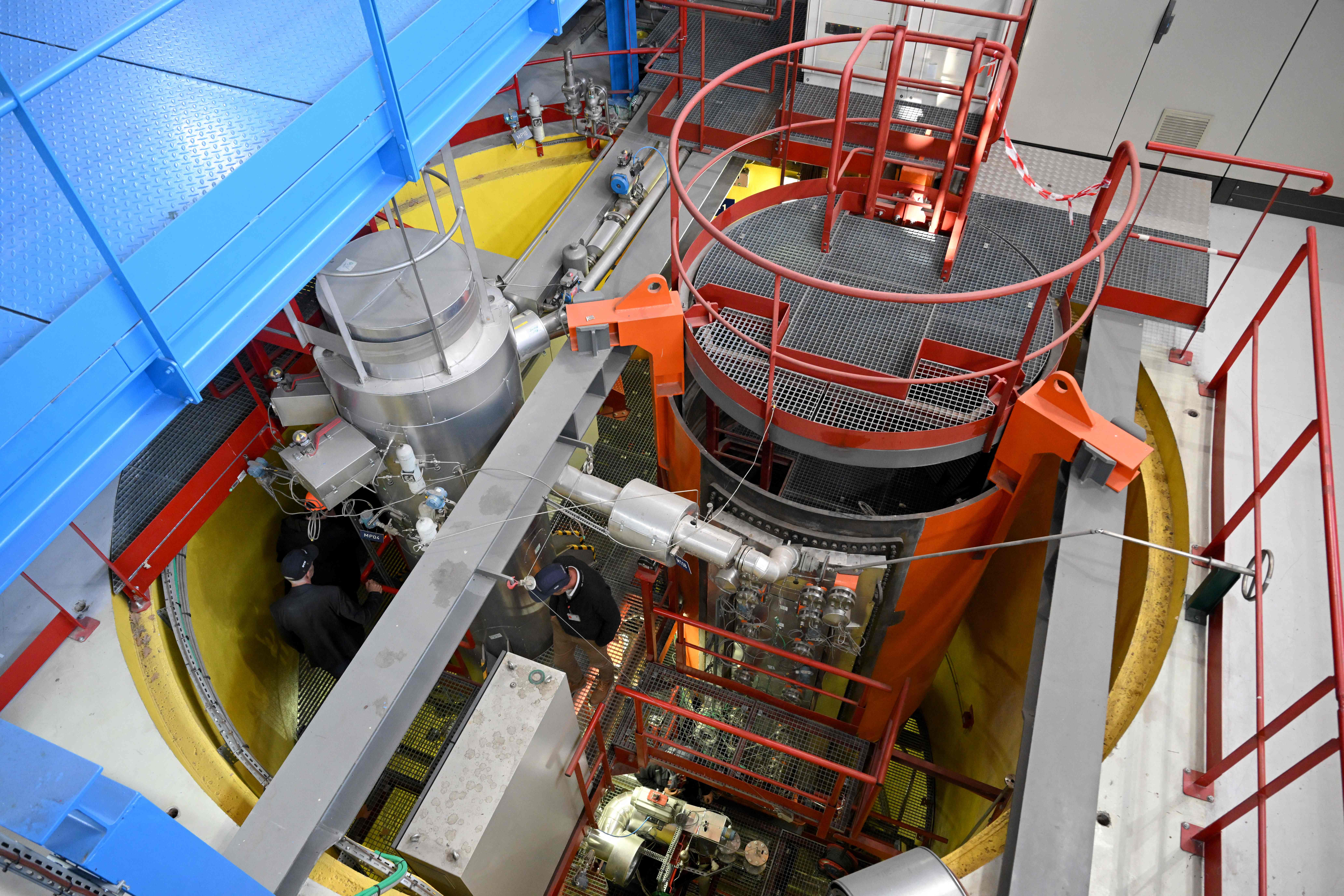Engineers walk in the Exocet installation of the Poseidon departement during a press visit to CEA Cadarache in Saint-Paul-les-Durances, southern France, on November 23, 2023. The Poseidon unit conducts experimental studies on Small Modular Reactors (SMR). An SMR is a nuclear fission reactor, smaller in size and power than conventional reactors, manufactured in a factory and transported to the installation site. Worldwide, research centers, start-ups and operators have embarked on a technological race to release the first SMR by the end of the decade or early 2030. (Photo by Nicolas TUCAT / AFP)